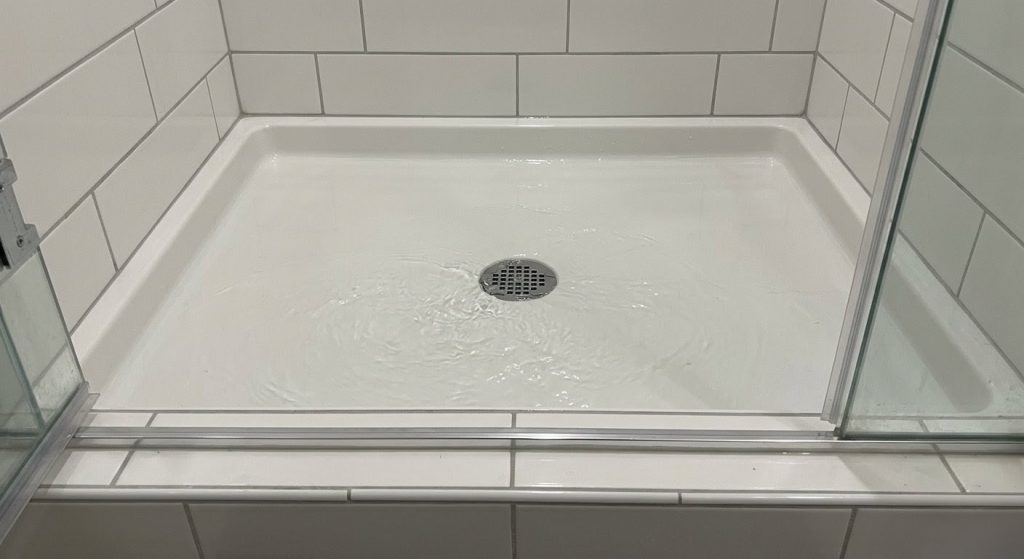 Water backed up and pooling over a shower drain, a key symptom of a main sewer line blockage in an Upland home.